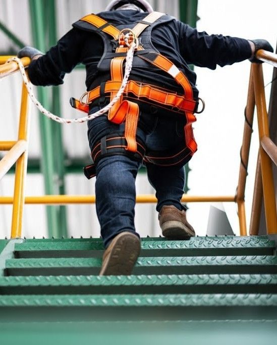 A man wearing safety harness climbing stairs